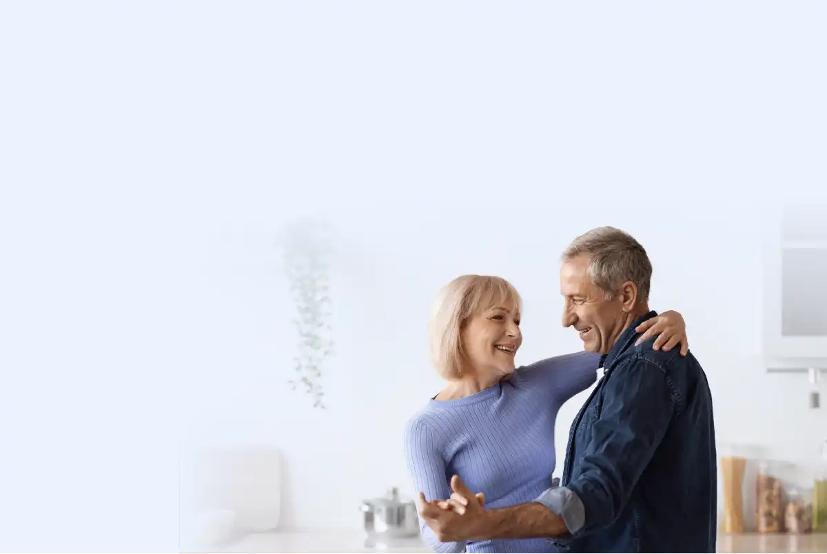 A smiling couple standing together in a kitchen.
